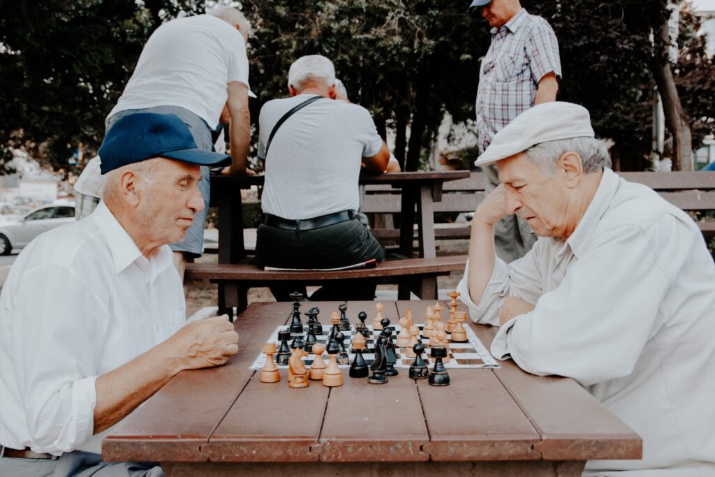 Dois idosos concentrados jogando xadrez do lado de fora